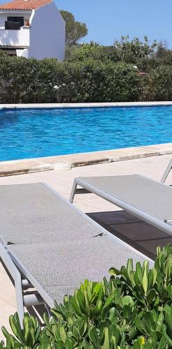 a bed next to a swimming pool in front of a pool at Aparthotel FLORA PARK & AQUAROCK in Cala en Bosc