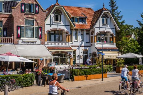 people riding bikes down a street in front of a building at Dijkstra Hotels in Bergen