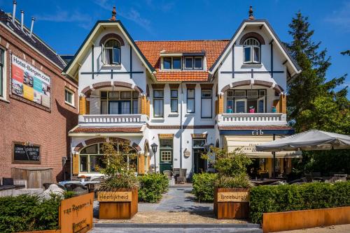 a large white house with a brick building at Dijkstra Hotels in Bergen