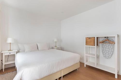 a white bedroom with a white bed and two tables at Apartment Marysol in Nazaré