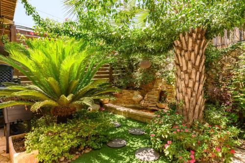 a garden with palm trees and plants in a yard at bali carmel zimmer & spa in Dāliyat el Karmil