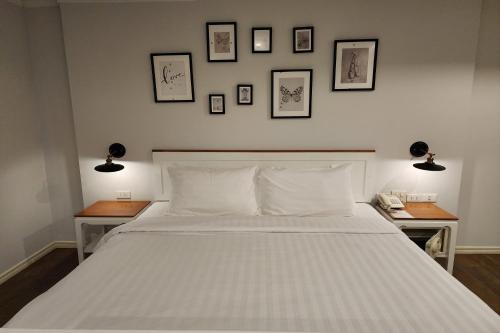 a bedroom with a white bed with three pictures on the wall at J PLACE HOTEL in Bangkok