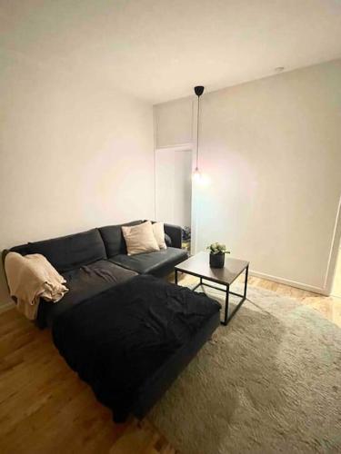 a living room with a black couch and a table at Two-room apartment in Stor København in Tåstrup