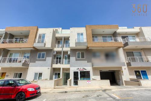 a red car parked in front of a building at Designer 1BR home with private balcony in Gharghur by 360 Estates in Għargħur