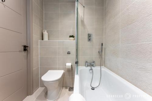 Un baño con bañera, inodoro y ducha. en Harbour View by Grandeur Property, en Poole