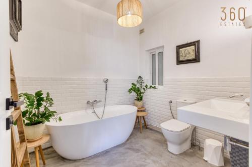 a bathroom with a white tub and a toilet and a sink at Designer 1BR home with private balcony in Gharghur by 360 Estates in Għargħur