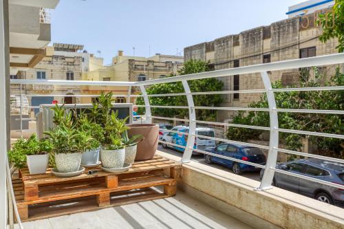 a balcony with potted plants and a view of a city at Designer 1BR home with private balcony in Gharghur by 360 Estates in Għargħur