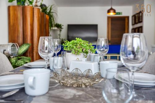 a table with wine glasses and plates on it at Designer 1BR home with private balcony in Gharghur by 360 Estates in Għargħur