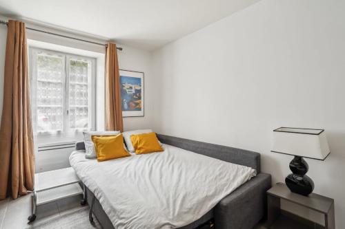 une chambre avec un lit avec des oreillers jaunes et une fenêtre dans l'établissement Magnifique Appart Spacieux Versailles 4Pers, à Buc