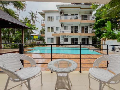 Un balcón con mesa y sillas y una piscina. en Rainforest Enclave, Arpora - 10 mins to Baga beach, en Arpora
