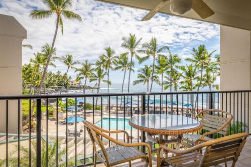 a balcony with a table and chairs and a view of the ocean at Aston Kona By The Sea in Kailua-Kona