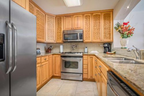 a kitchen with wooden cabinets and a stainless steel refrigerator at Aston Kona By The Sea in Kailua-Kona