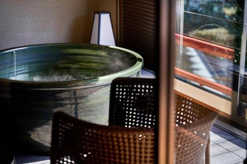a large tub sitting next to two chairs next to a window at Mansuirou in Misasa