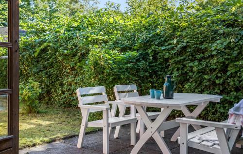 a white picnic table and two chairs sitting next to a hedge at Gorgeous Home In Jerup With Wifi in Jerup