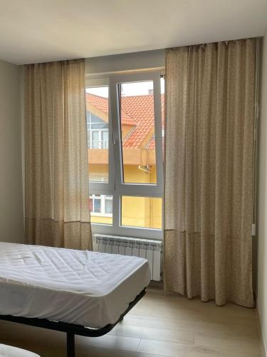 a bedroom with a bed and a large window at Apartamento Recién Reformado en Somo junto iglesia in Somo
