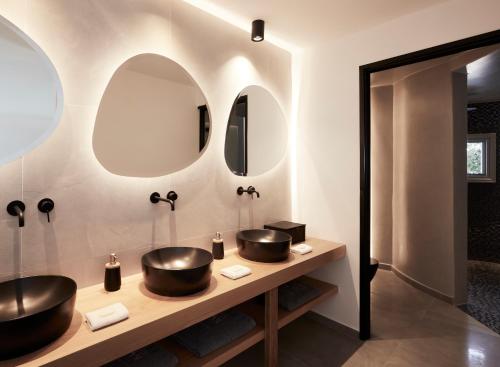 two sinks in a bathroom with two mirrors at Kalisti Hotel & Suites in Fira