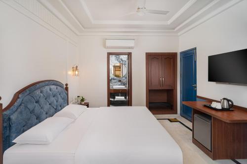 a bedroom with a large bed and a television at Hotel Ganga Maiya in Lucknow
