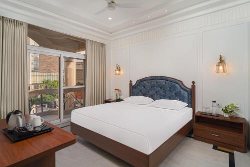 a bedroom with a large white bed and a balcony at Hotel Ganga Maiya in Lucknow