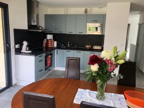 une cuisine avec une table avec un vase de fleurs dessus dans l'établissement TUAMOTU - Location 3 Chambres le Bourget du Lac Chambéry, au Bourget-du-Lac
