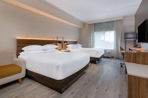 a hotel room with two beds and a television at Wyndham Garden Orlando Airport - Free Airport Shuttle in Orlando