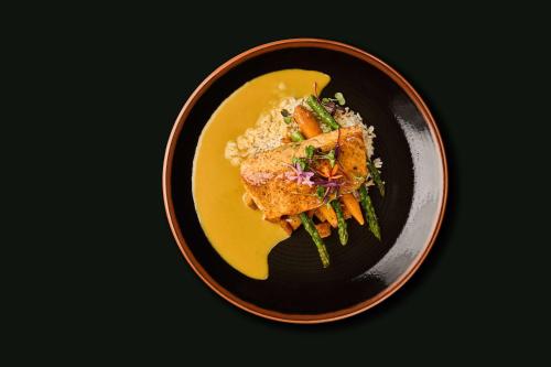 a black plate of food with meat and vegetables at The Leta Santa Barbara Goleta, Tapestry Collection by Hilton in Santa Barbara