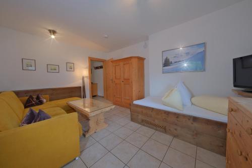 a living room with a couch and a tv at Chalet Stubai inklusive Stubai Super Card in Fulpmes