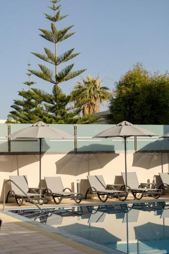 a group of chairs and umbrellas next to a swimming pool at Athina Beach Hotel in Kato Daratso