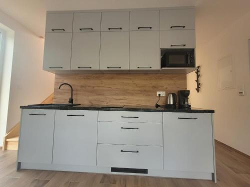 a kitchen with white cabinets and a black counter top at Parkcity SPA Domek z jacuzzi w górach in Biała Niżna