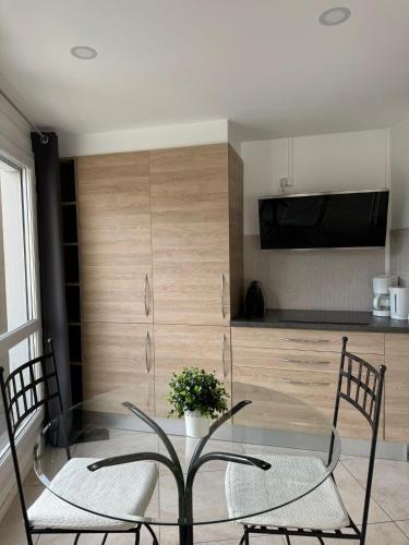 a dining room with a glass table and two chairs at Appart' Hôtel Fauriel Saint-Etienne Parking privé balcon wifi in Saint-Étienne