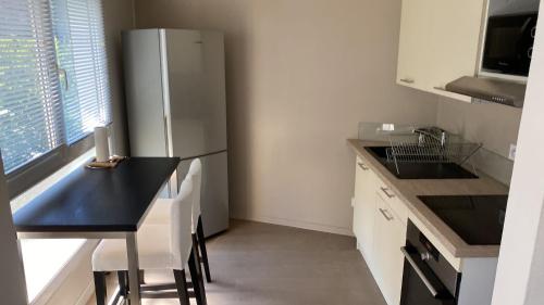a kitchen with a black table and a refrigerator at Appart' Hôtel Fauriel Saint-Etienne Parking privé balcon wifi in Saint-Étienne