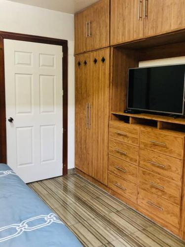 a bedroom with a flat screen tv and wooden cabinets at Departamento Céntrico, acogedor, comodo, pequeño in Orizaba