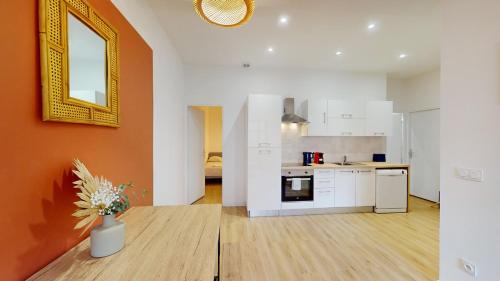 - une cuisine avec des placards blancs et un mur orange dans l'établissement T3 Spacieux - Proche gare - Entièrement rénové, à Marseille