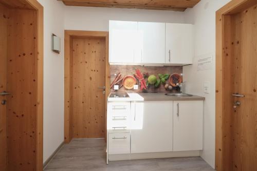 a kitchen with white cabinets and wooden walls at Chalet Stubai inklusive Stubai Super Card in Fulpmes
