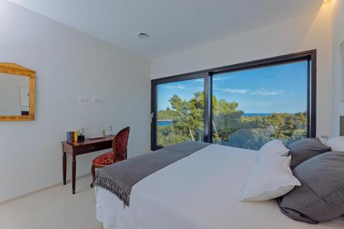 a bedroom with a bed and a large window at Stylish Lumbarda Villa Sleeps 10 with Private Pool in Lumbarda