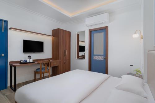 a white bedroom with a bed and a desk at Hotel Ganga Maiya in Lucknow
