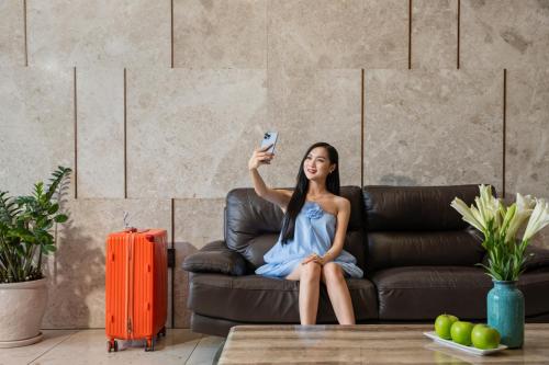 a woman sitting on a couch holding a remote control at Nostalgia Boutique Hotel in Da Nang