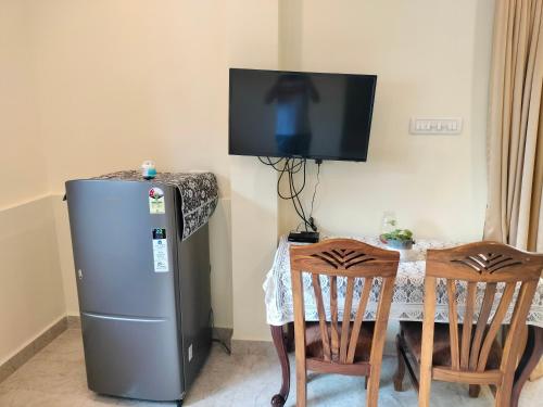 a small refrigerator and a table with a television on a wall at Primavera Holiday Homes-FAMILY RUN GOAN GUEST HOUSE in Candolim