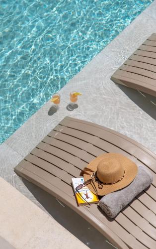 a hat and a book next to a swimming pool at Pavlina Villa , a hidden gem with heated pool and ping pong! in Perama