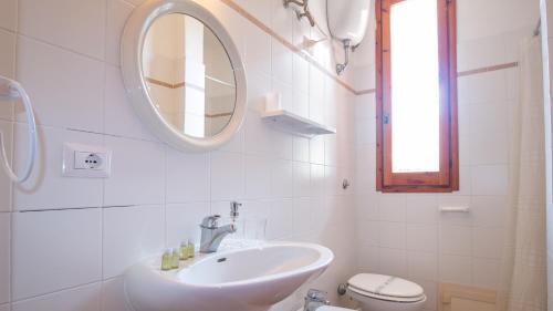 a white bathroom with a sink and a mirror at Villa Brezza di Mare-Geremeas Country Club in Maracalagonis