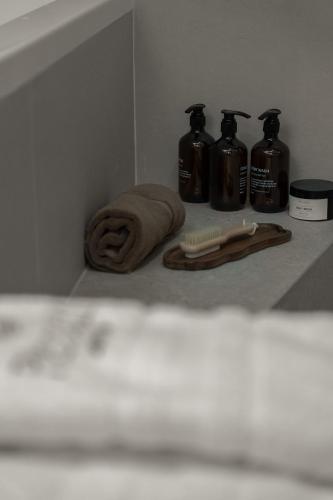 a shelf with three bottles of soap and a towel at Piccadill Luxury Villas in Methoni
