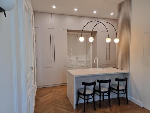 a kitchen with a island with four chairs and a sink at Apartamenty Inspiracja in Kraków