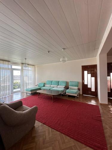 a living room with blue chairs and a red rug at Tagaytay Karakol Hotel in Karakol
