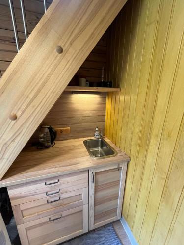a kitchen with a sink and a wooden wall at Cozy Forest Cabin in Kadaga