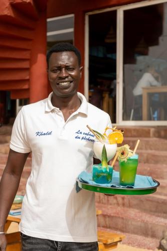 a man holding a tray with two drinks on it at La Cabane du Pêcheur Atlantic Evasion in Dakar