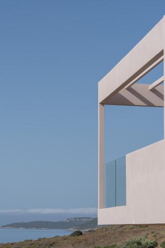 a house on a hill with the ocean in the background at Piccadill Luxury Villas in Methoni