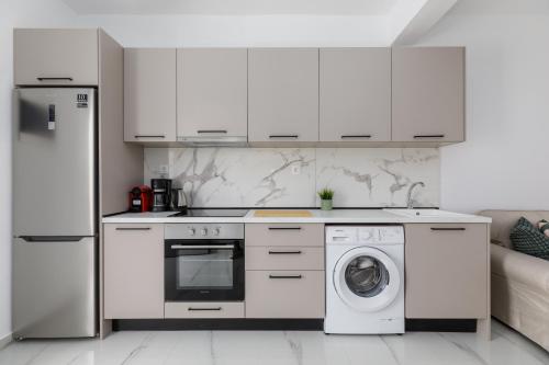 a kitchen with white cabinets and a washer and dryer at Kiwi by halu!, Apartments in Perea in Perea