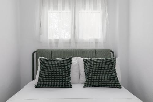 a bed with two pillows in front of a window at Kiwi by halu!, Apartments in Perea in Perea