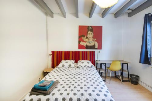 Un dormitorio con una cama y un escritorio y un cuadro. en Vacances Pays Basque, en Bidart