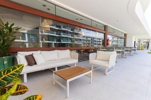 a restaurant with white furniture and tables and chairs at Makia Beach #D205 - Flat em Ipojuca by Carpediem in Porto De Galinhas