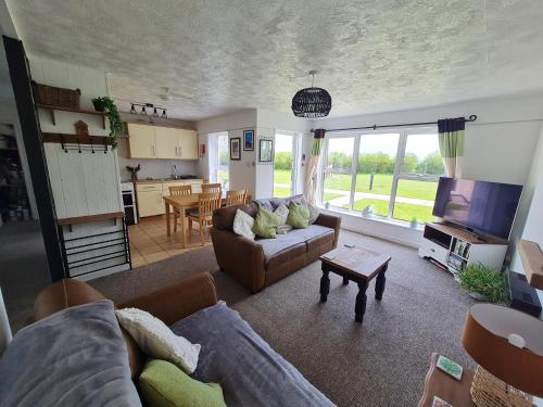 a living room with a couch and a table and a kitchen at Perran View Holiday Park in St. Agnes